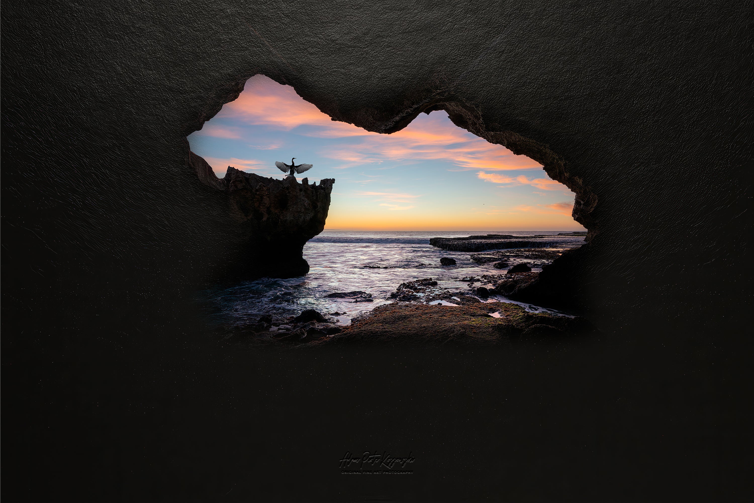 Sunset over the ocean viewed through a natural rock formation