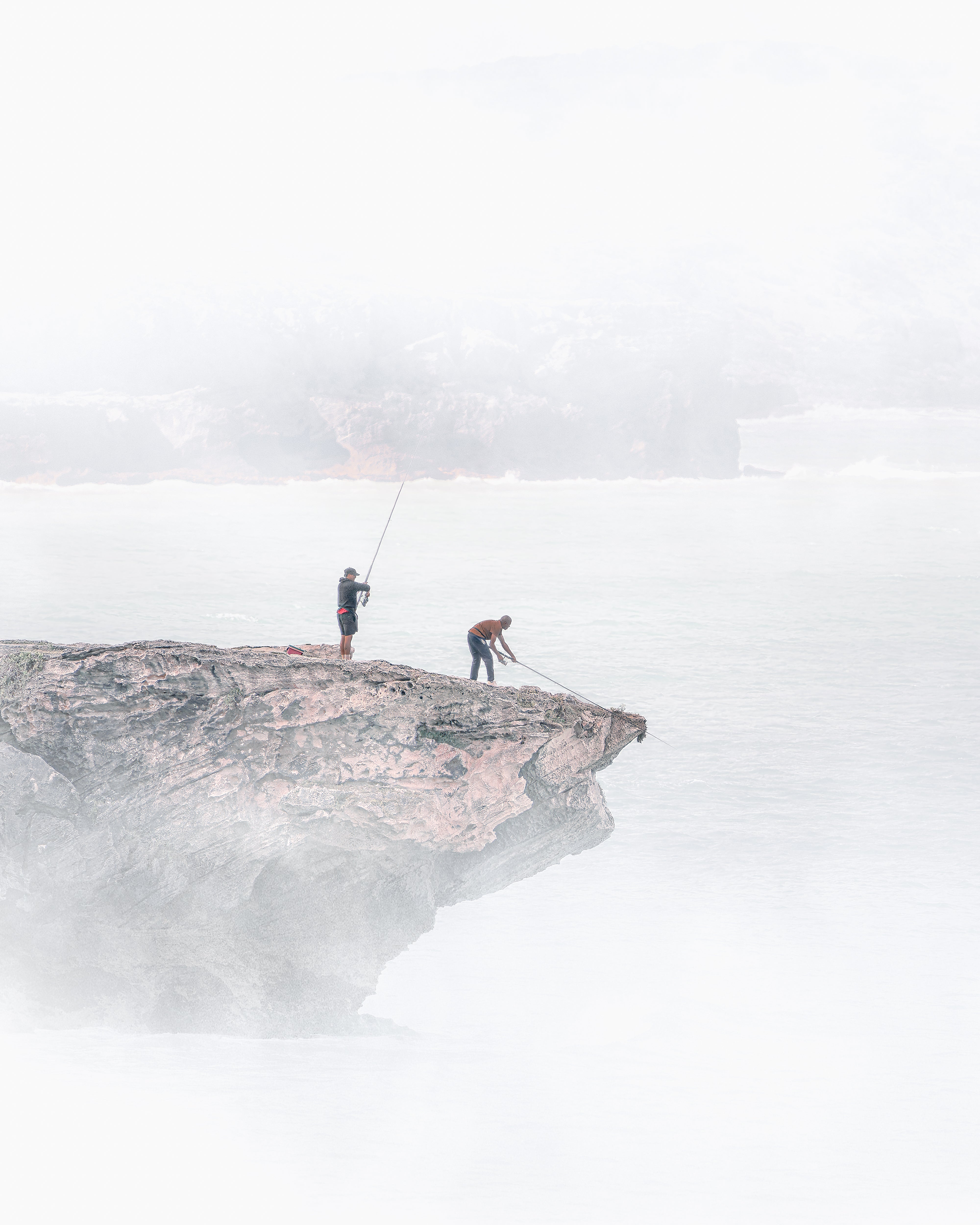 Two climbers on a rocky outcrop with a foggy landscape